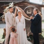 Freie Trauung mit Brautpaar und Trauredner vor rustikaler Hochzeitskulisse